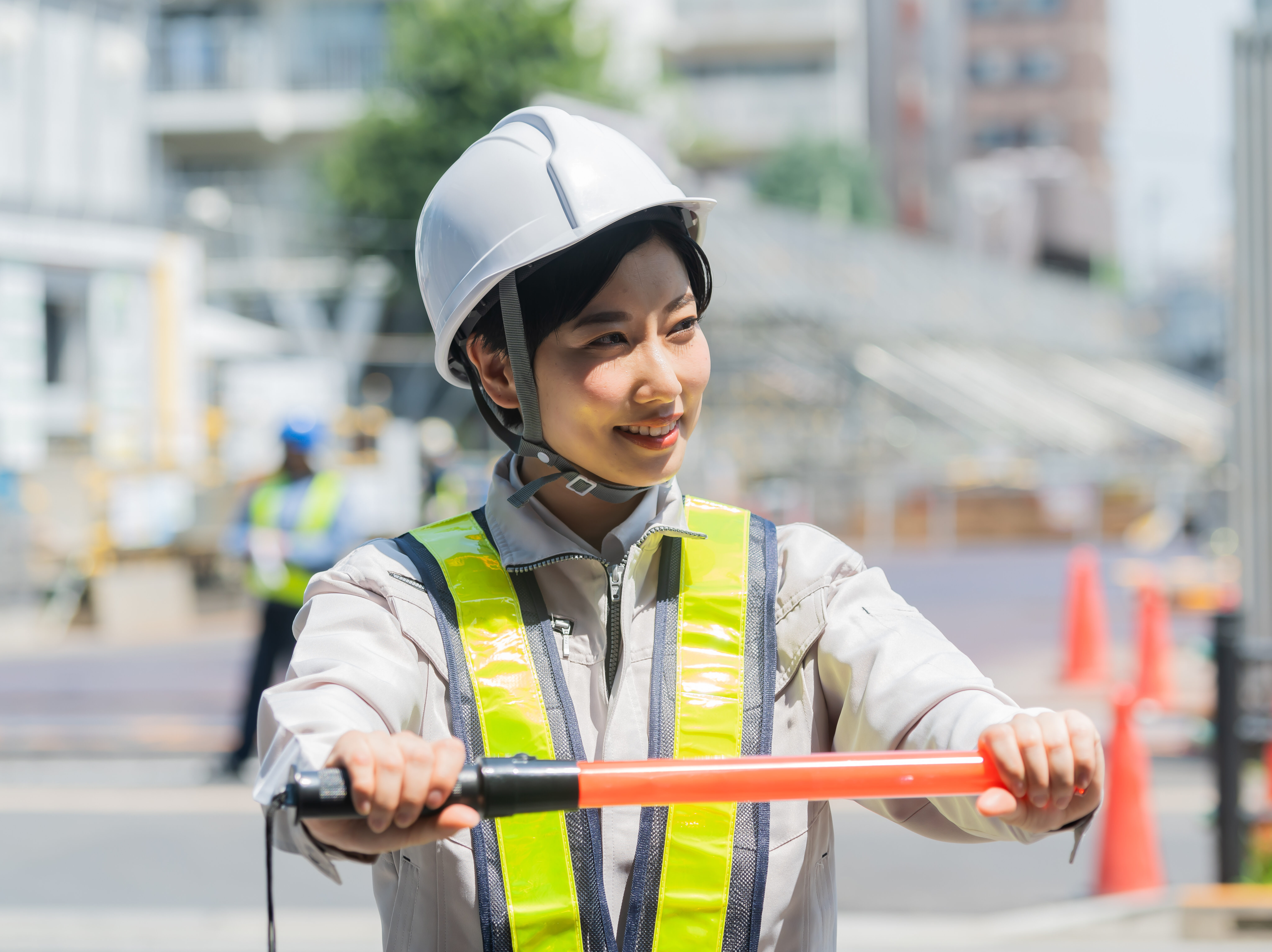 誘導棒を持ち工事現場で働く女性